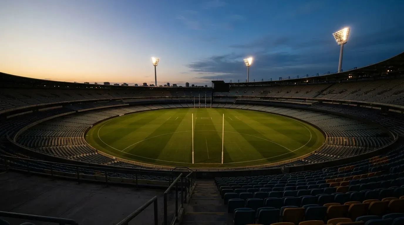An empty football stadium with floodlight masts at dusk