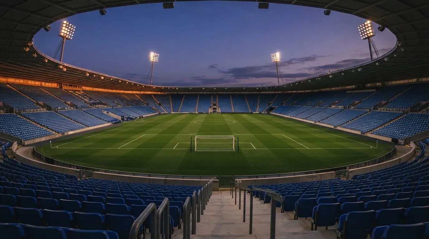 An empty football stadium with floodlight masts at dusk