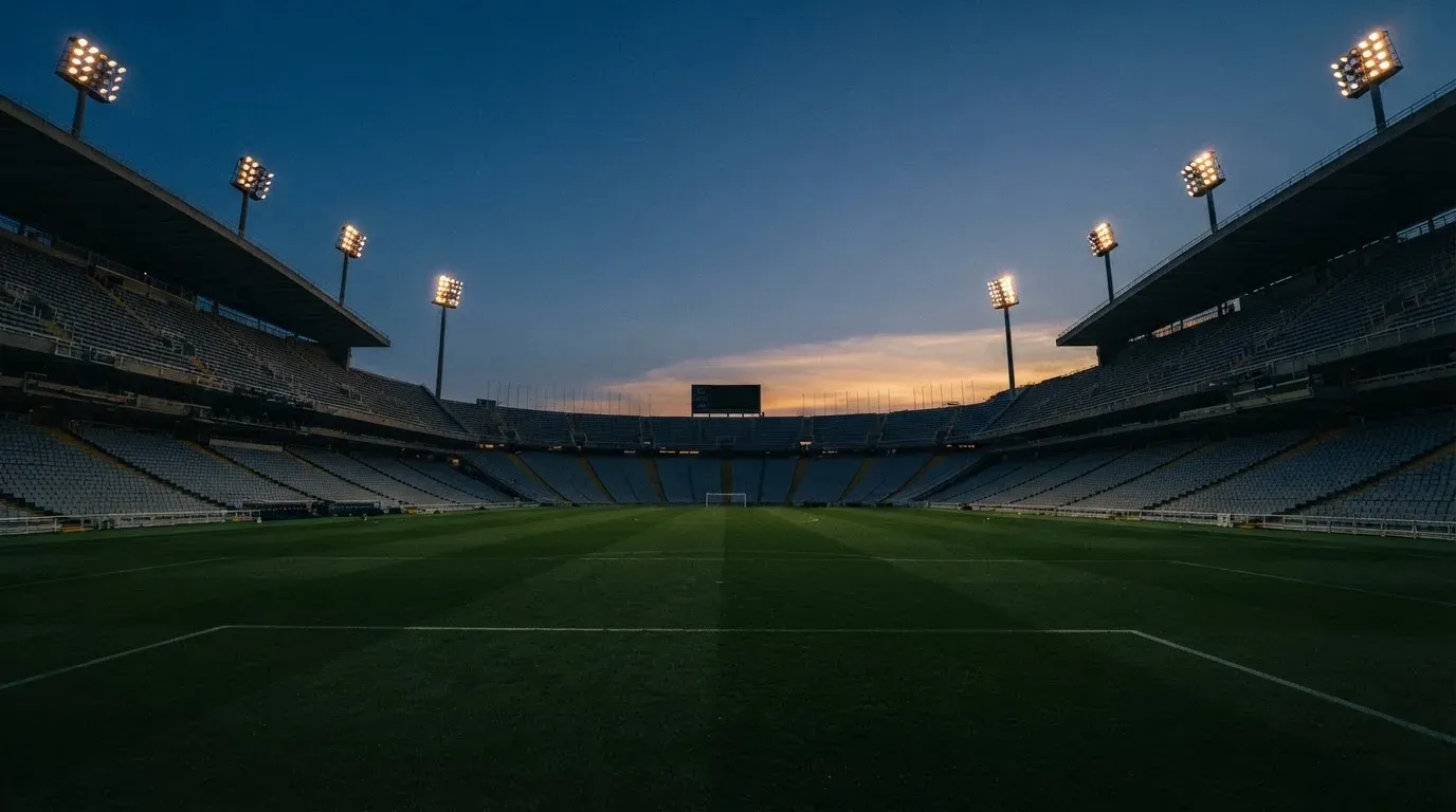 An empty football stadium with floodlight masts at dusk