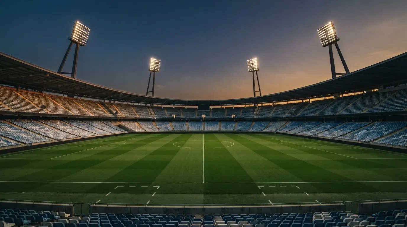 An empty football stadium with floodlight masts at dusk