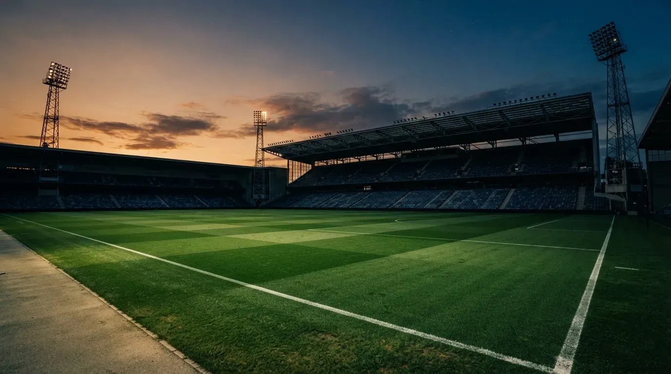An empty football stadium with floodlight masts at dusk
