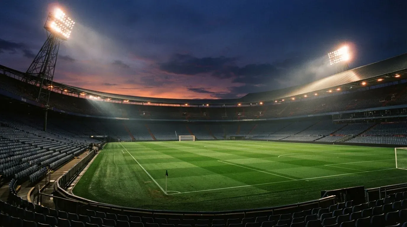 An empty football stadium with floodlight masts at dusk