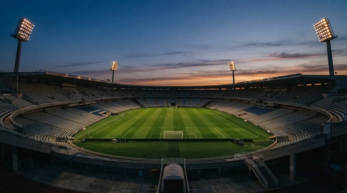 An empty football stadium with floodlight masts at dusk