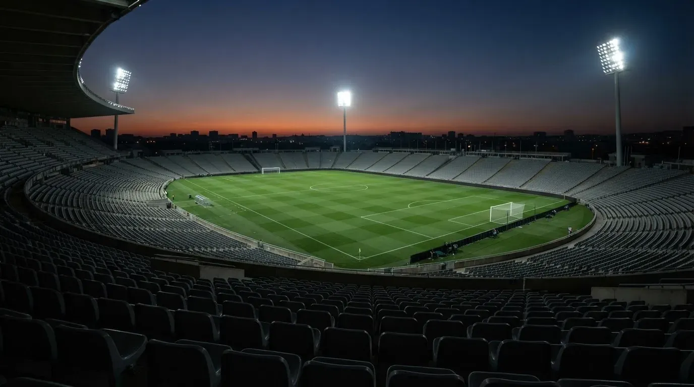 An empty football stadium with floodlight masts at dusk