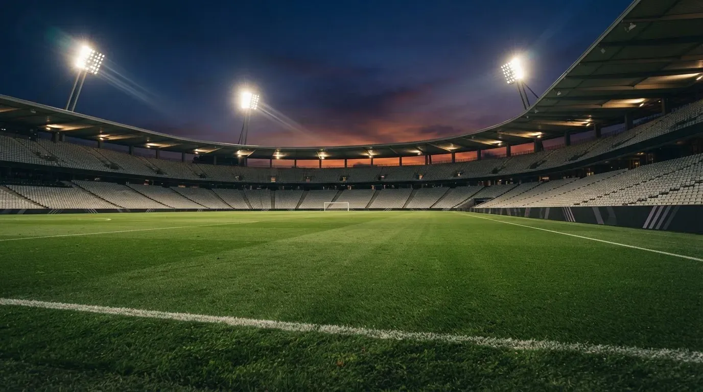 An empty football stadium with floodlight masts at dusk