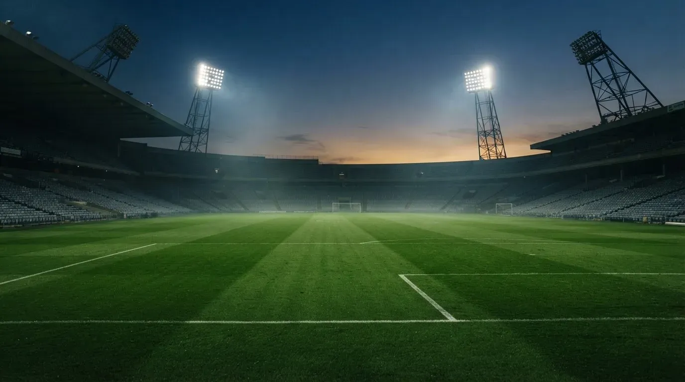 An empty football stadium with floodlight masts at dusk