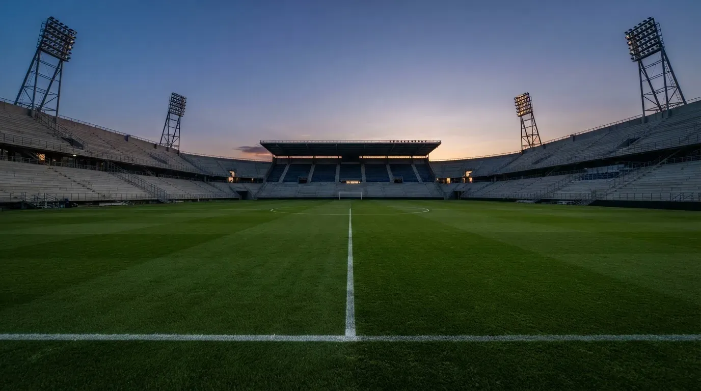 An empty football stadium with floodlight masts at dusk