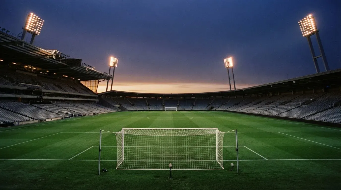 An empty football stadium with floodlight masts at dusk
