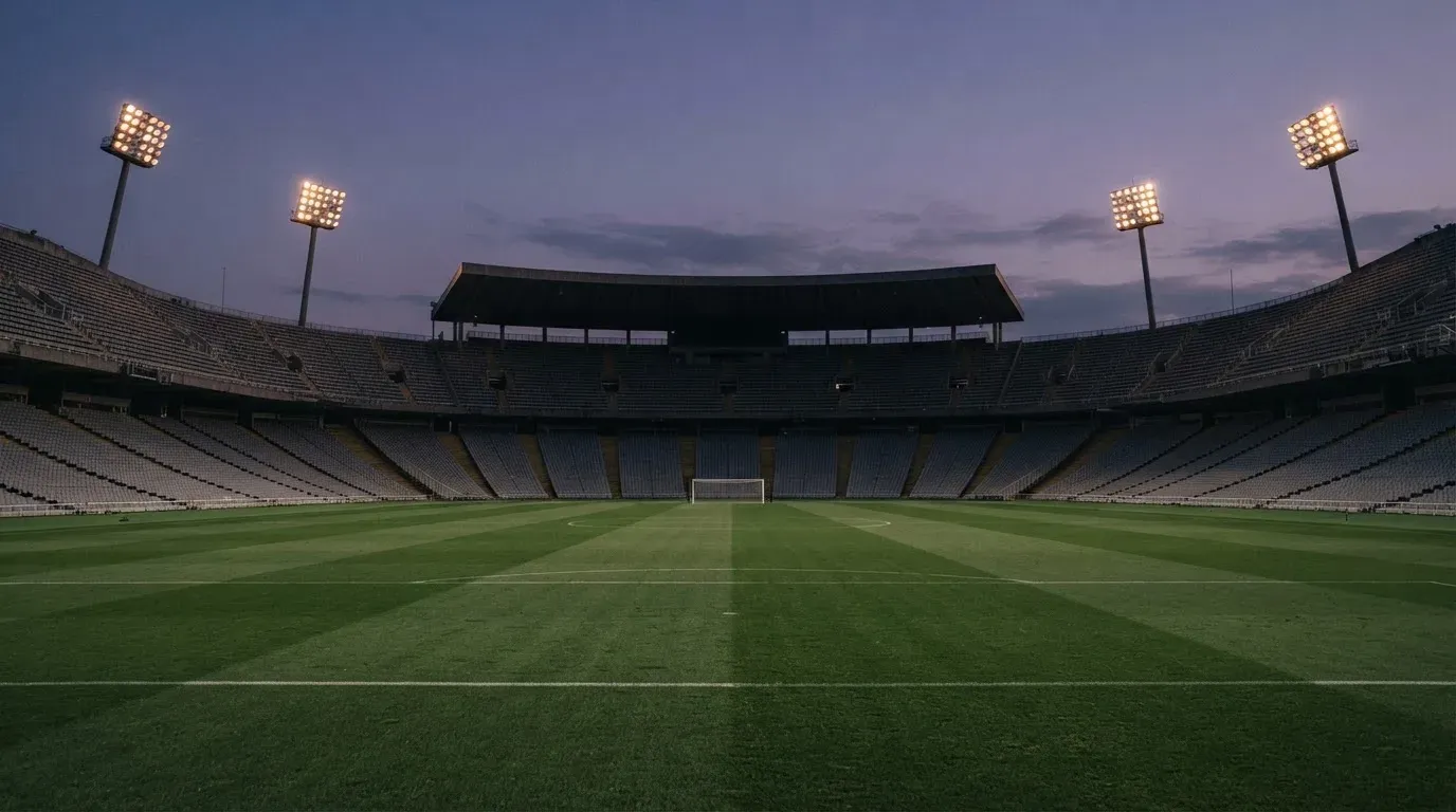 An empty football stadium with floodlight masts at dusk