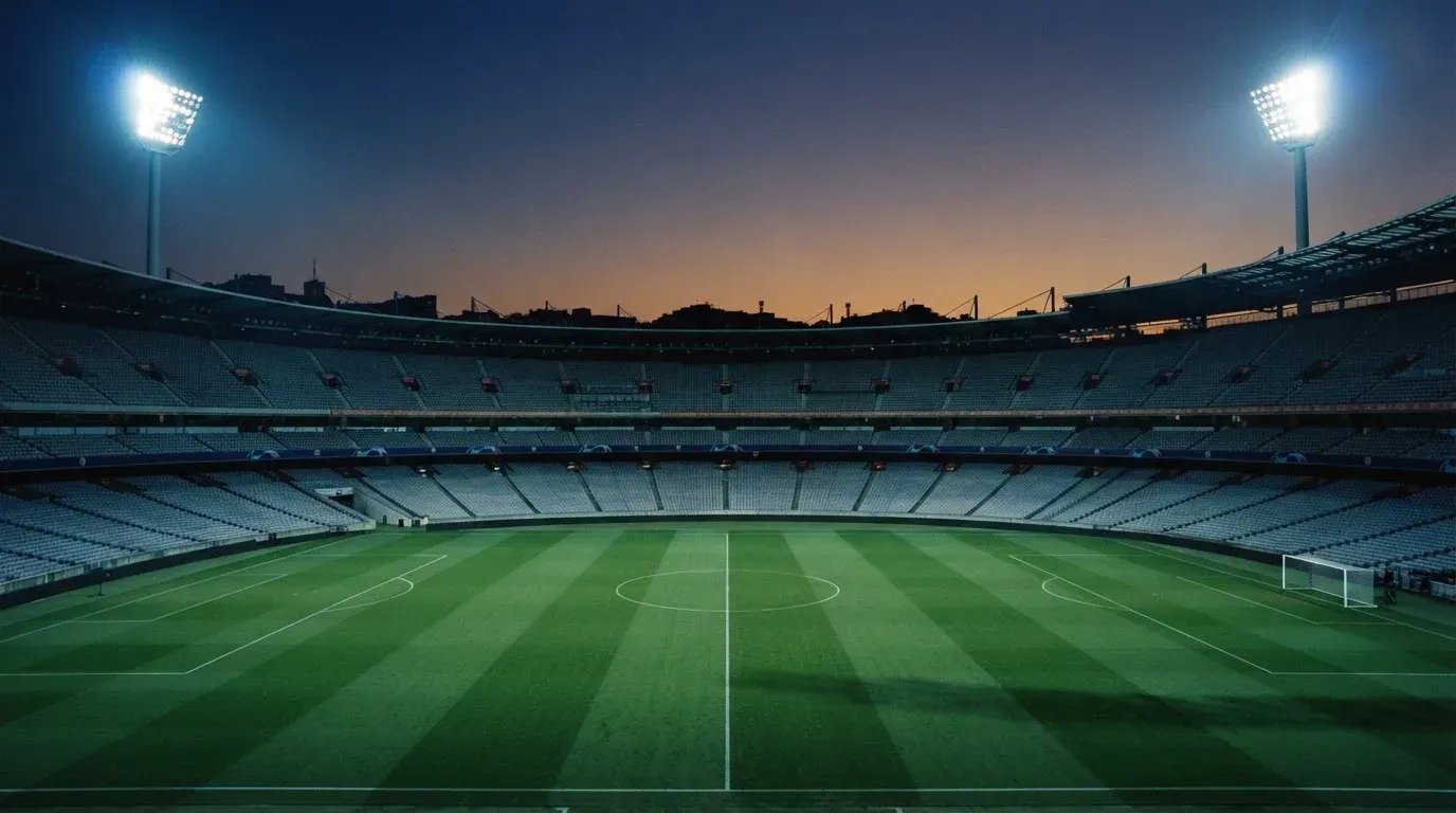 An empty football stadium with floodlight masts at dusk