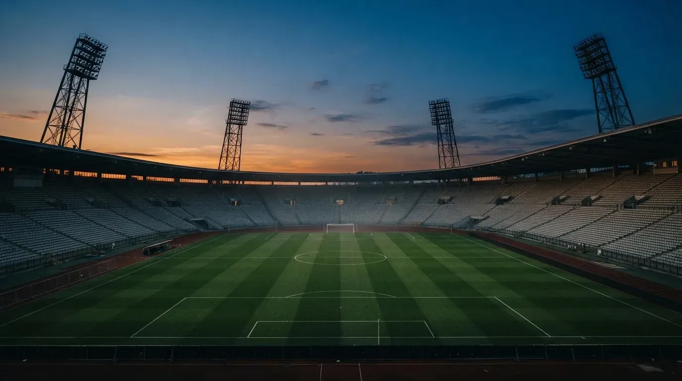 An empty football stadium with floodlight masts at dusk