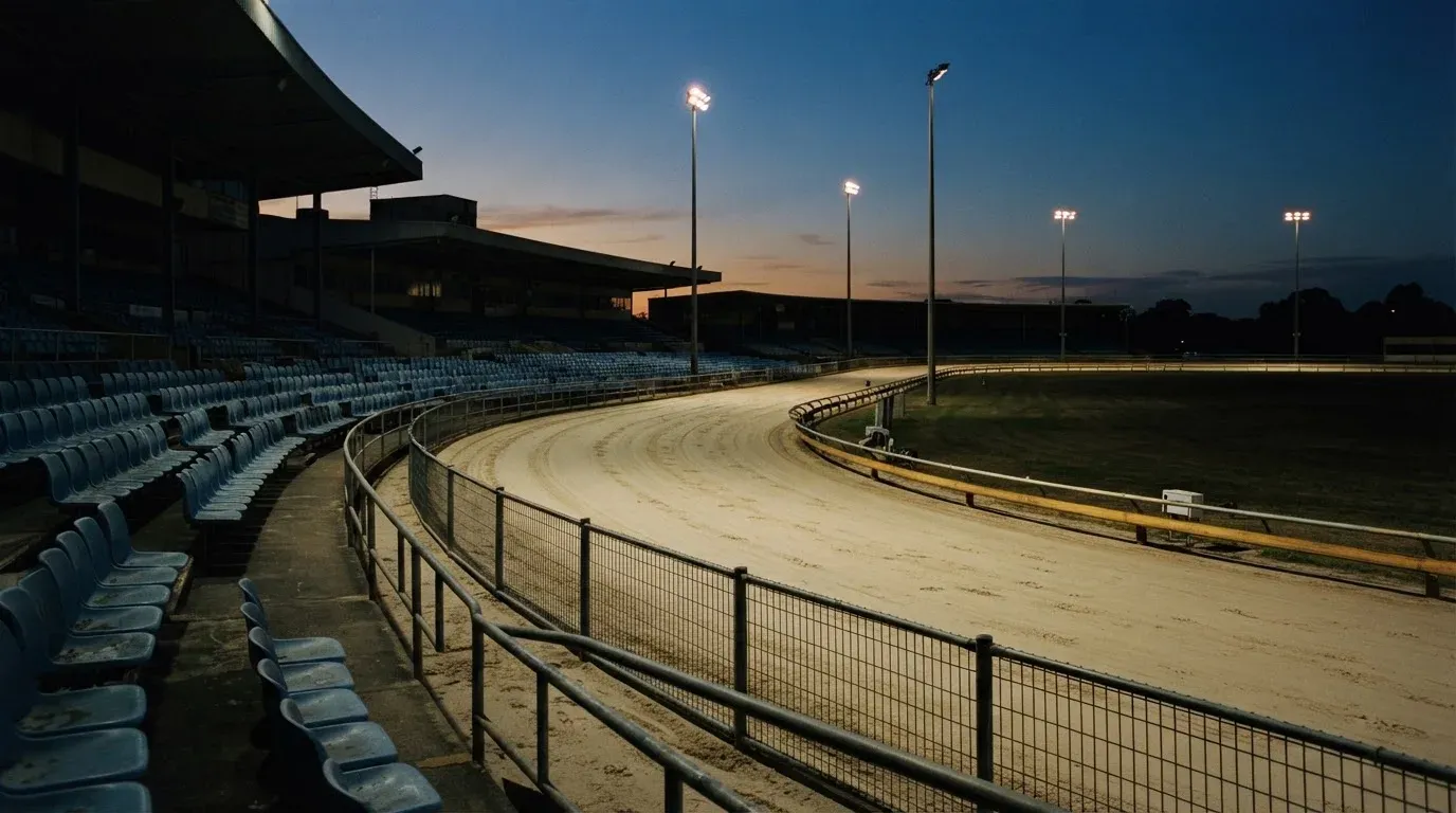 An empty football stadium with floodlight masts at dusk
