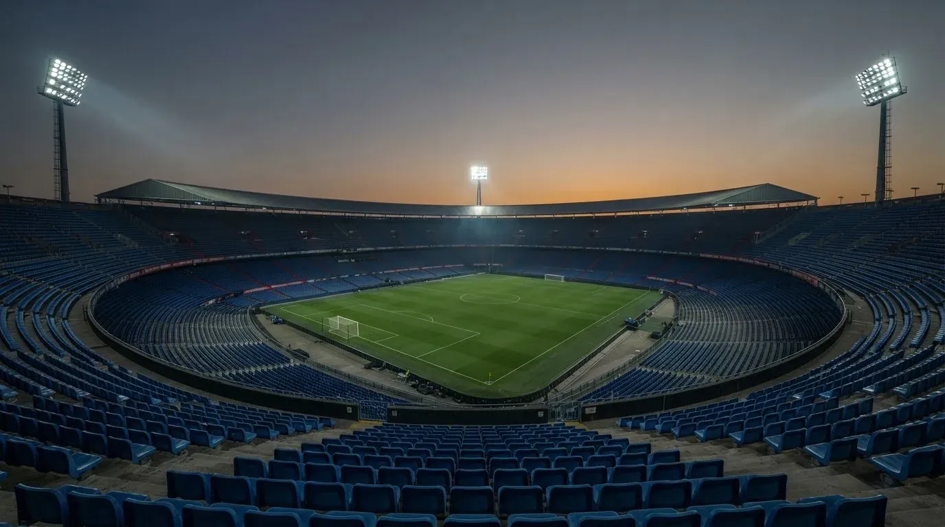 An empty football stadium with floodlight masts at dusk