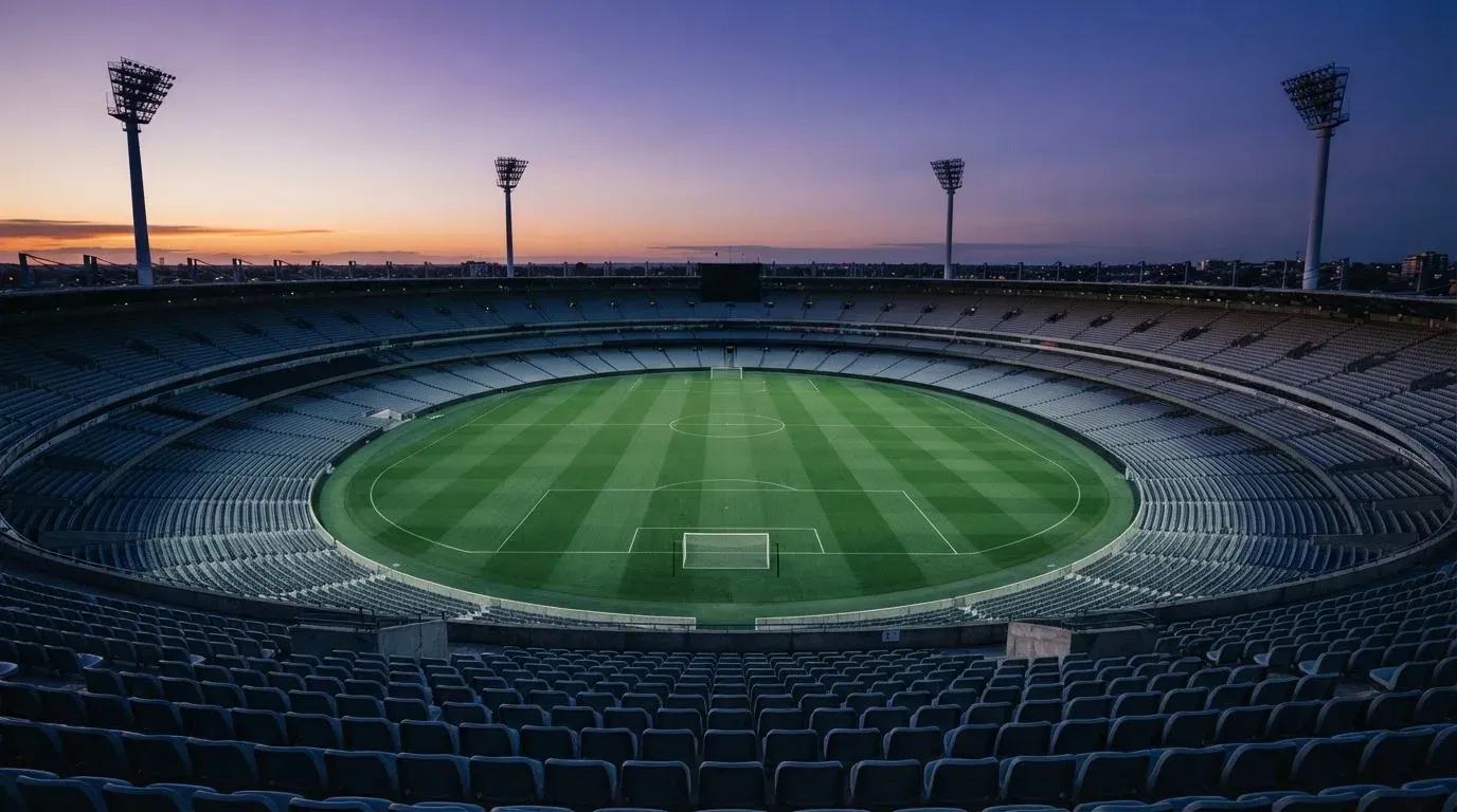 An empty football stadium with floodlight masts at dusk