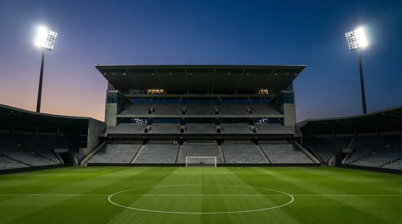 An empty football stadium with floodlight masts at dusk