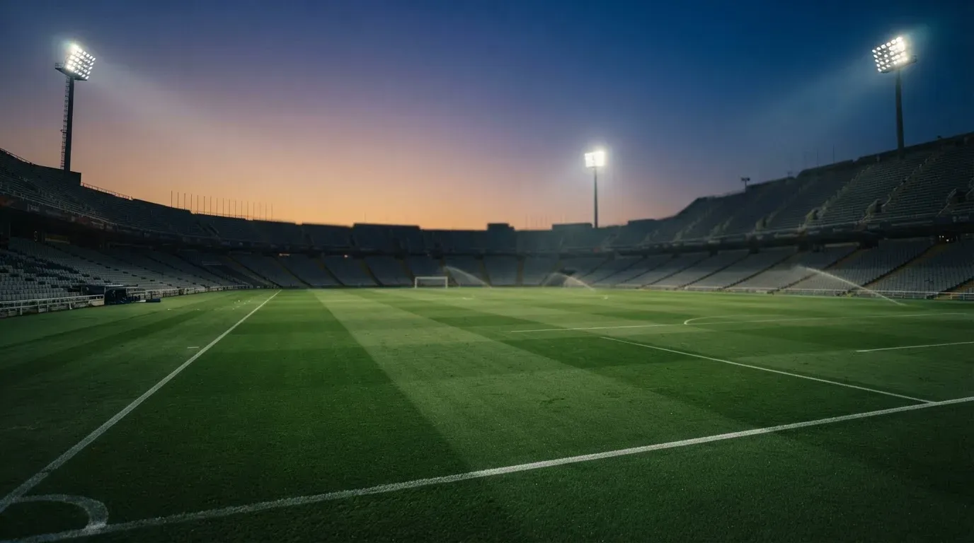 An empty football stadium with floodlight masts at dusk