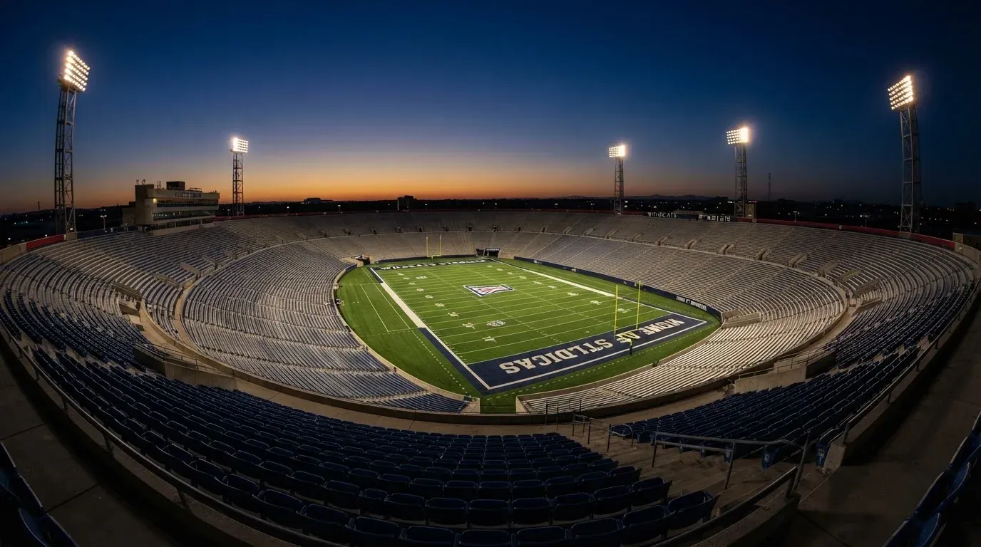 An empty football stadium with floodlight masts at dusk