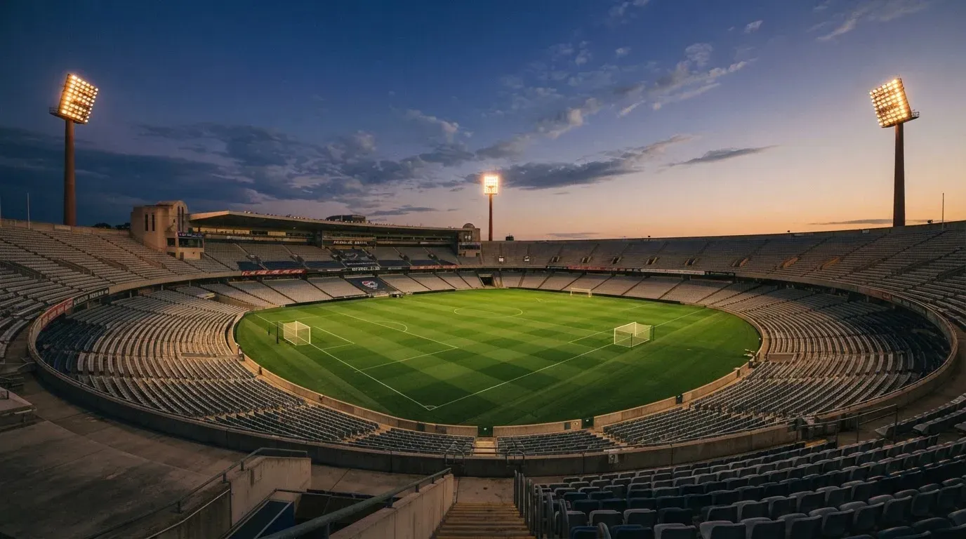 An empty football stadium with floodlight masts at dusk