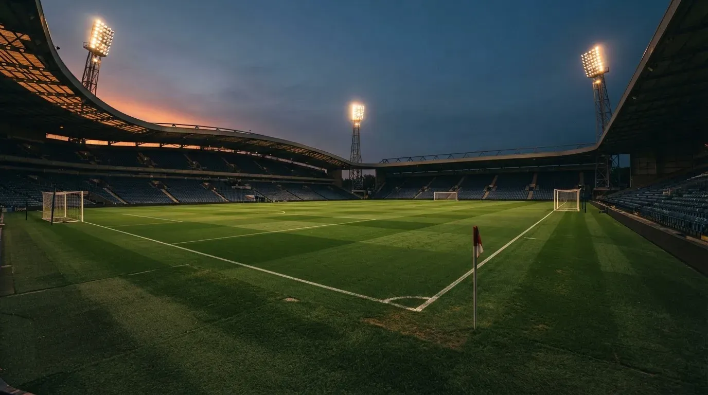 An empty football stadium with floodlight masts at dusk