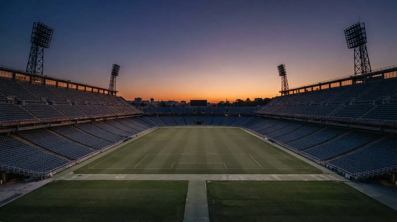 An empty football stadium with floodlight masts at dusk