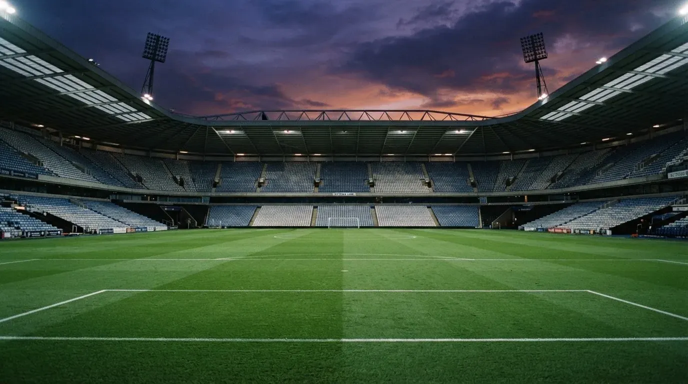 An empty football stadium with floodlight masts at dusk
