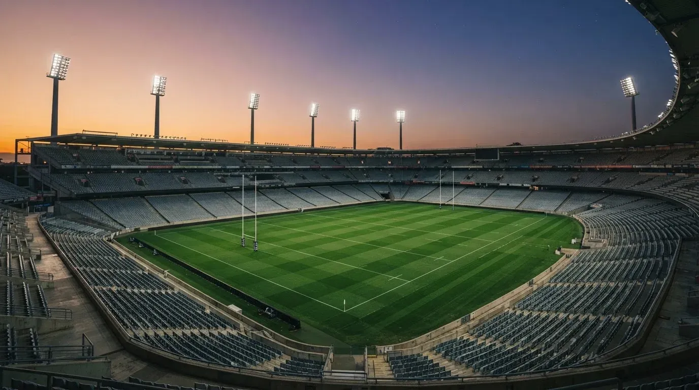 An empty football stadium with floodlight masts at dusk