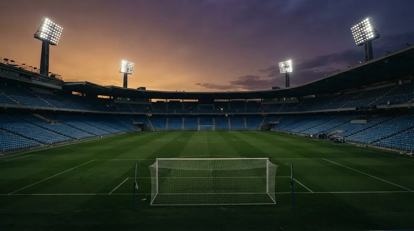 An empty football stadium with floodlight masts at dusk