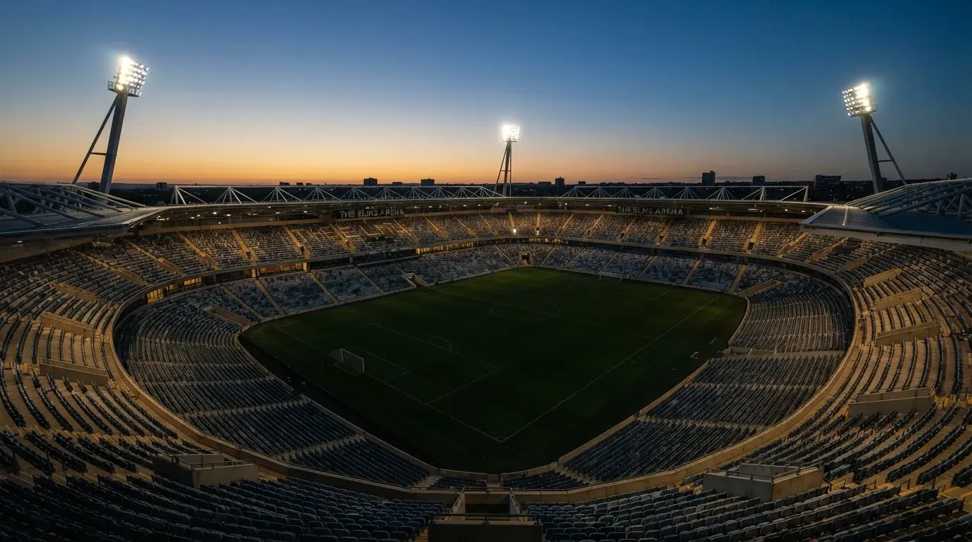 An empty football stadium with floodlight masts at dusk