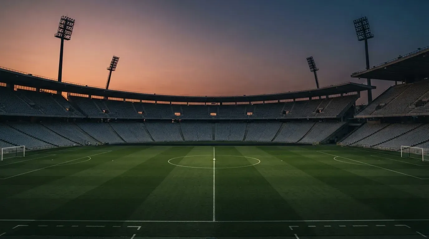 An empty football stadium with floodlight masts at dusk