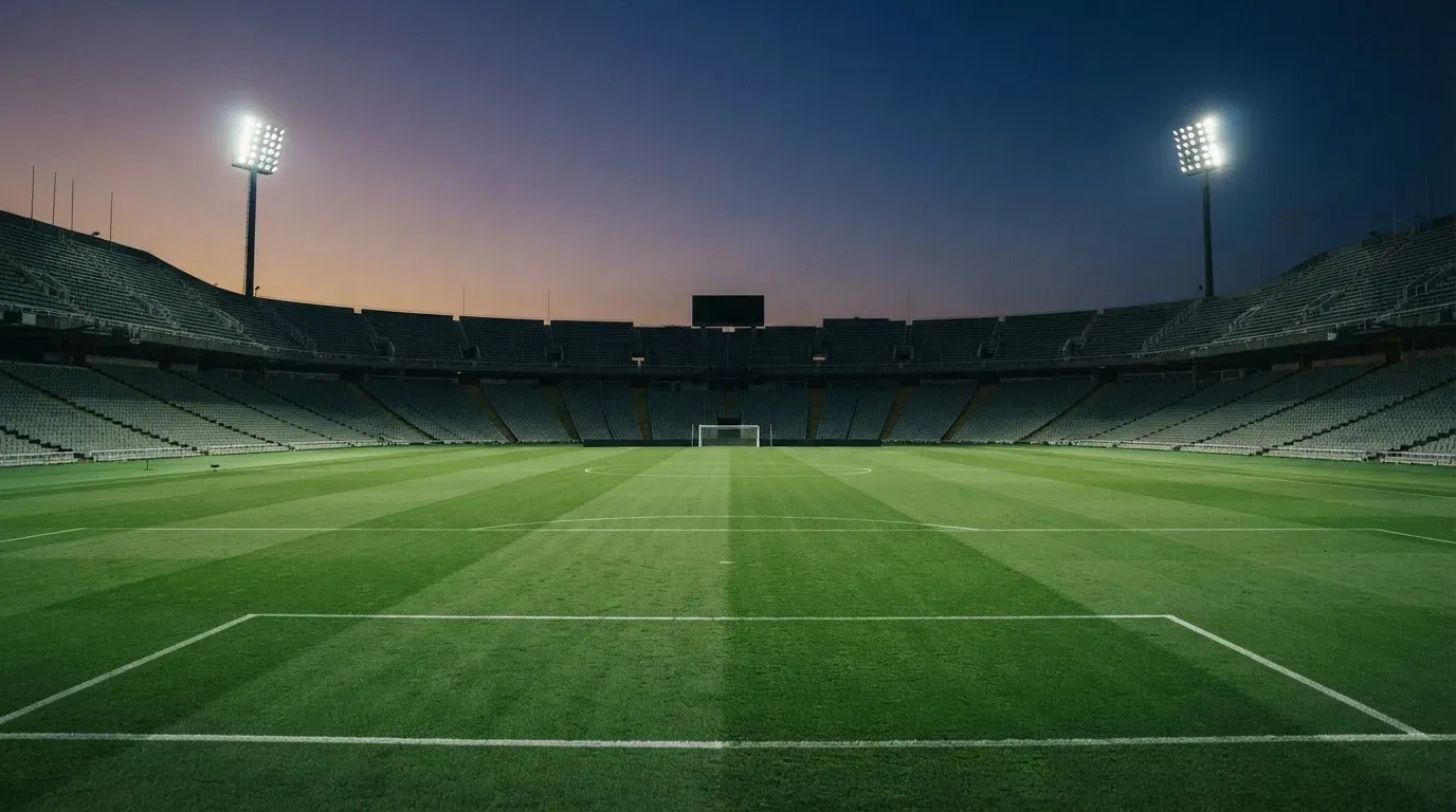 An empty football stadium with floodlight masts at dusk