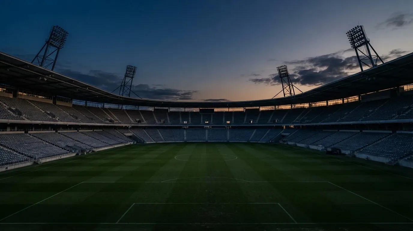 An empty football stadium with floodlight masts at dusk