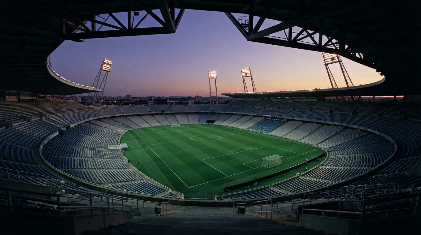 An empty football stadium with floodlight masts at dusk