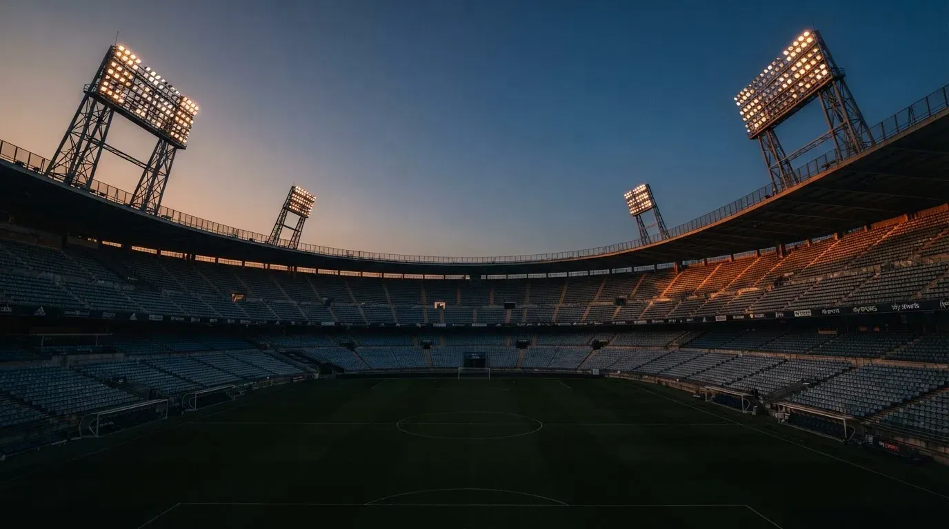 An empty football stadium with floodlight masts at dusk