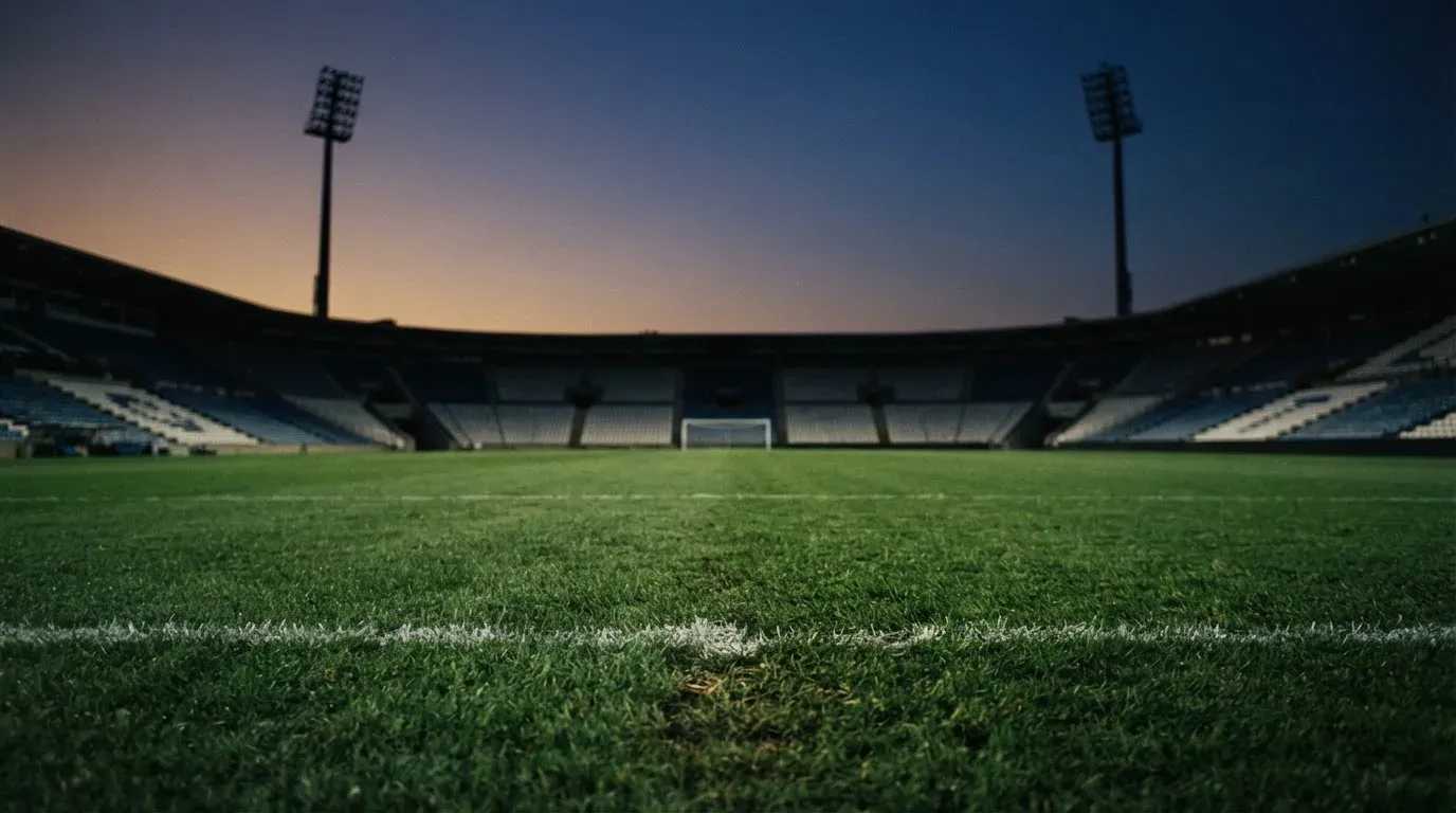 An empty football stadium with floodlight masts at dusk