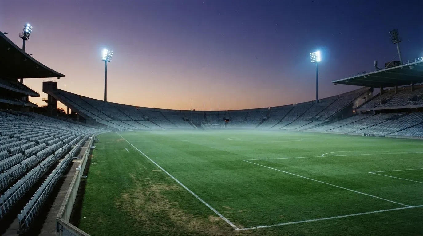 An empty football stadium with floodlight masts at dusk