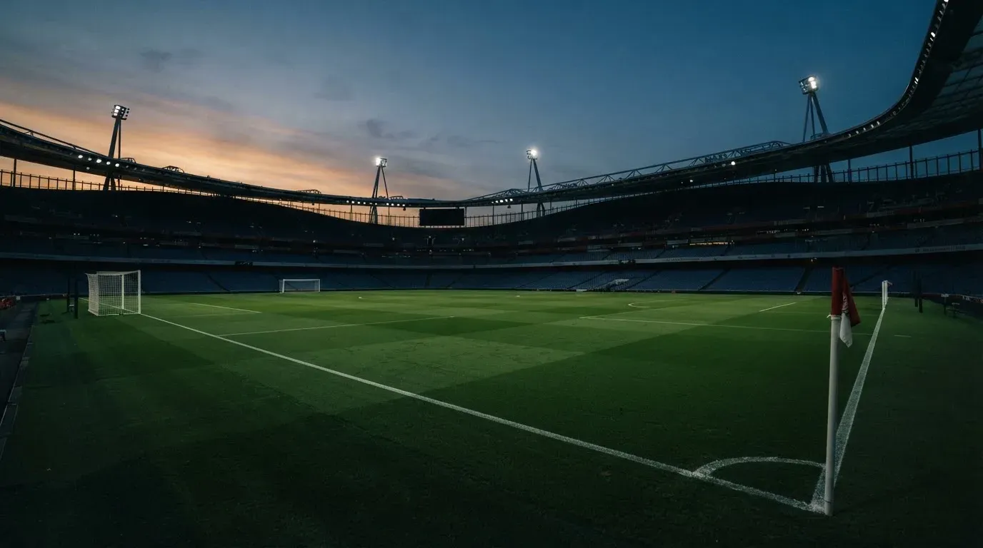 An empty football stadium with floodlight masts at dusk