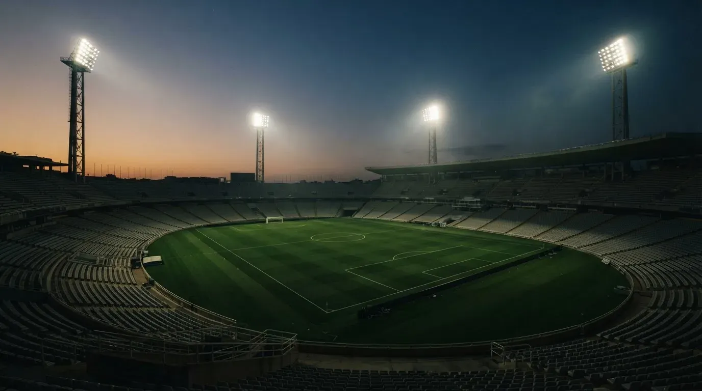 An empty football stadium with floodlight masts at dusk
