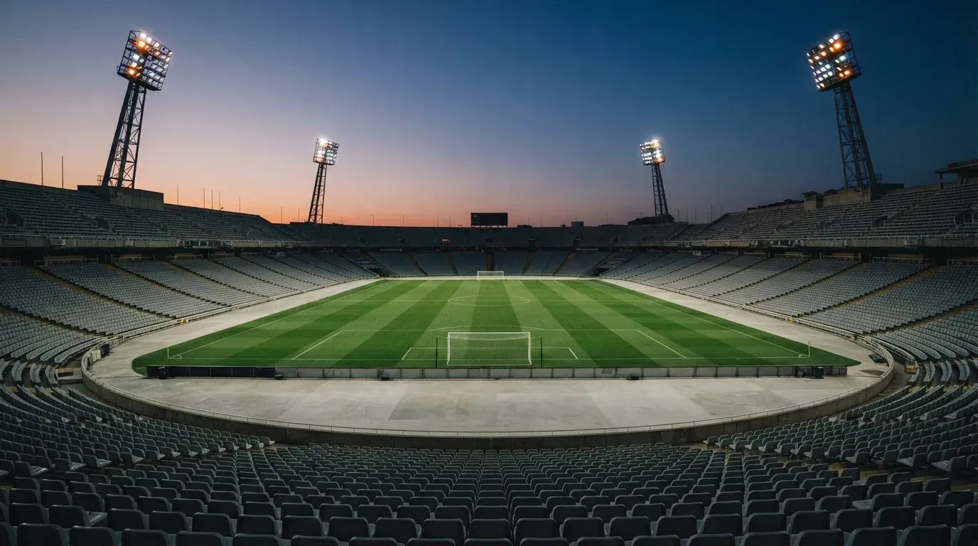 An empty football stadium with floodlight masts at dusk