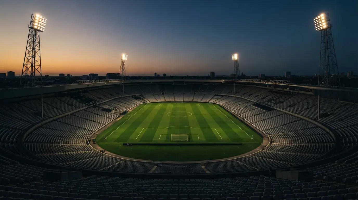 An empty football stadium with floodlight masts at dusk