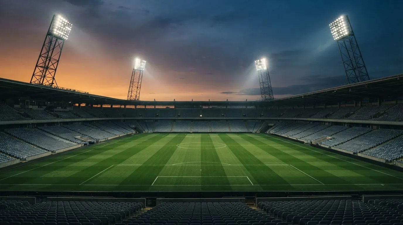 An empty football stadium with floodlight masts at dusk
