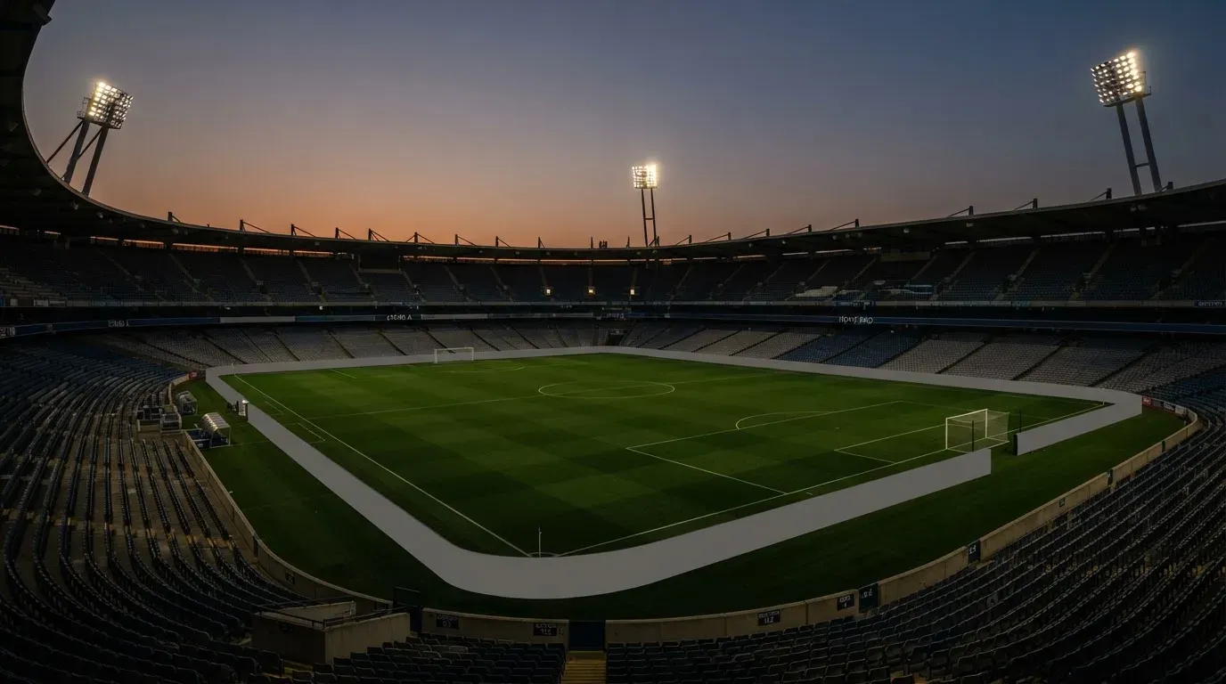 An empty football stadium with floodlight masts at dusk
