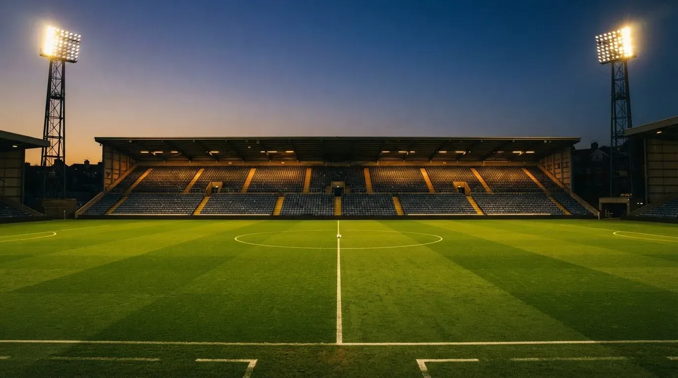 An empty football stadium with floodlight masts at dusk