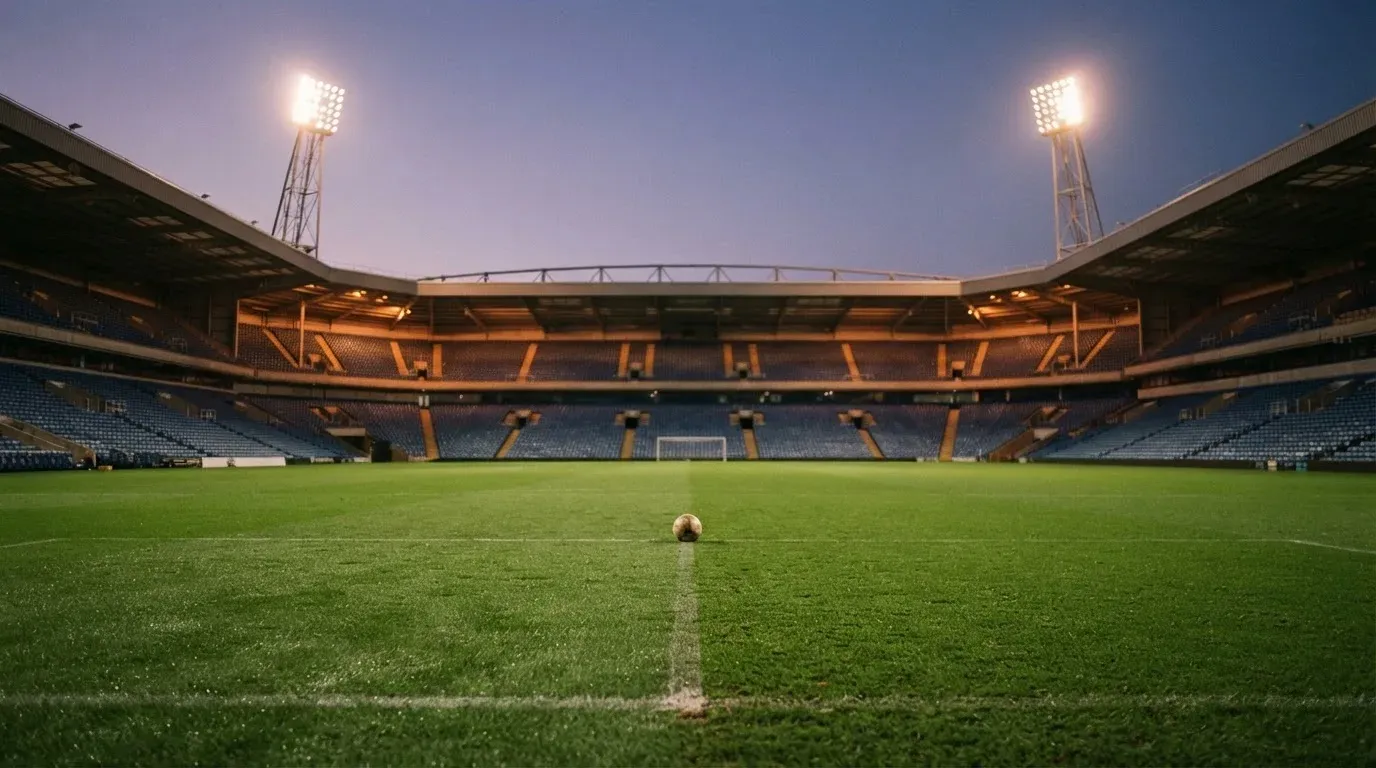 An empty football stadium with floodlight masts at dusk