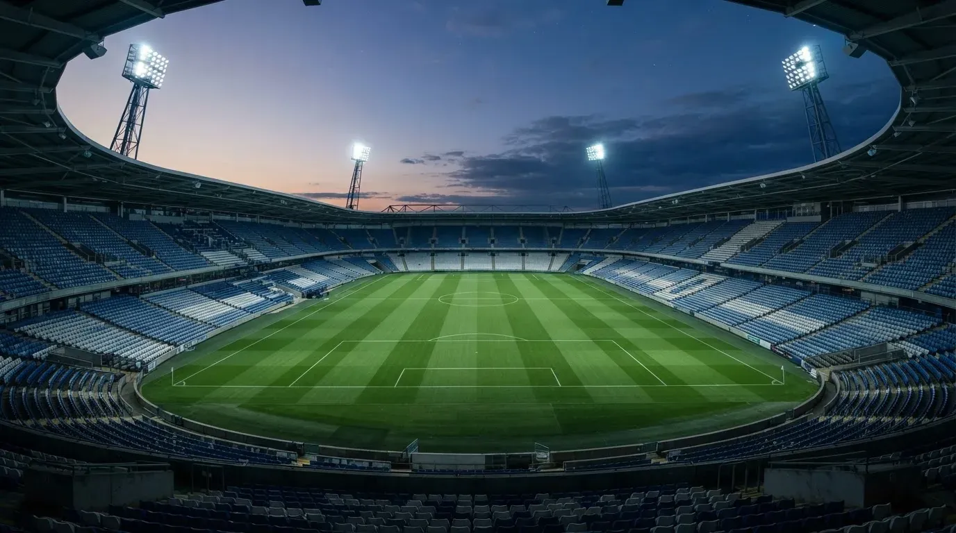 An empty football stadium with floodlight masts at dusk