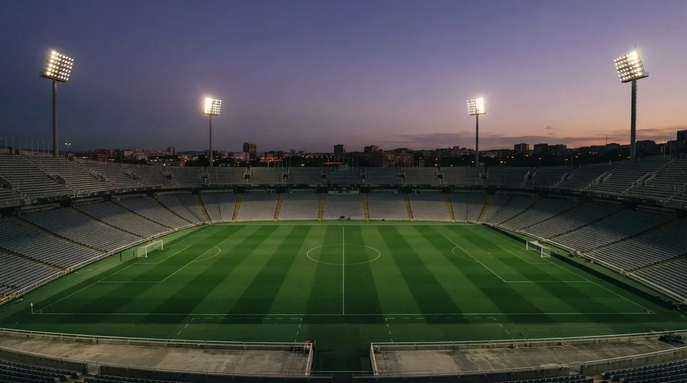 An empty football stadium with floodlight masts at dusk