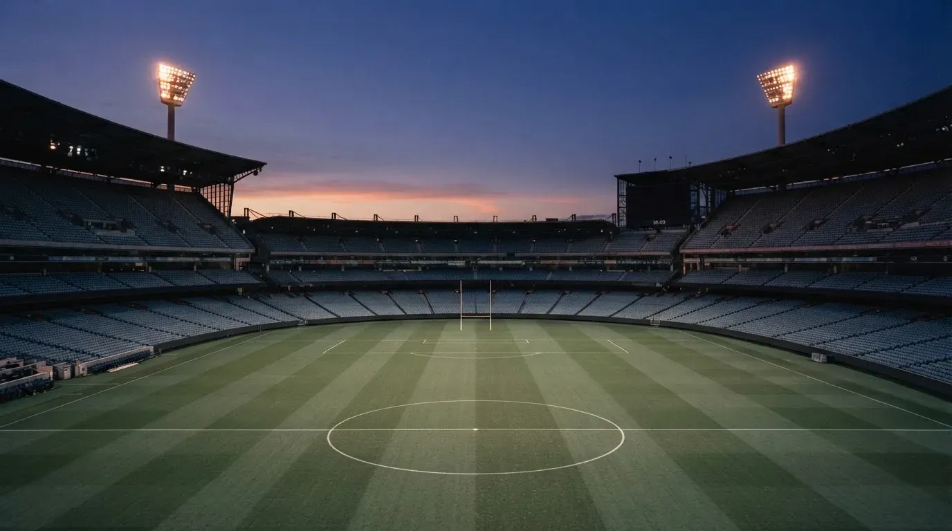 An empty football stadium with floodlight masts at dusk