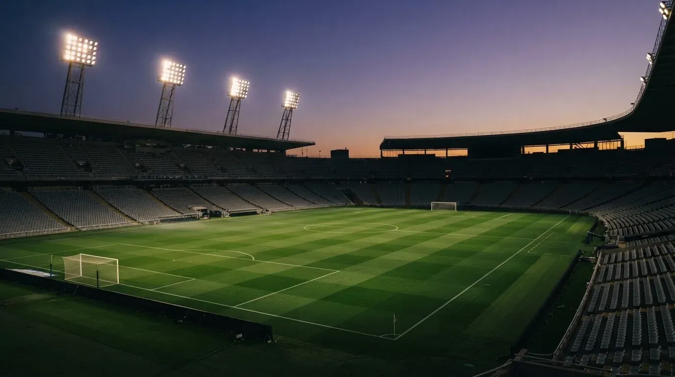 An empty football stadium with floodlight masts at dusk