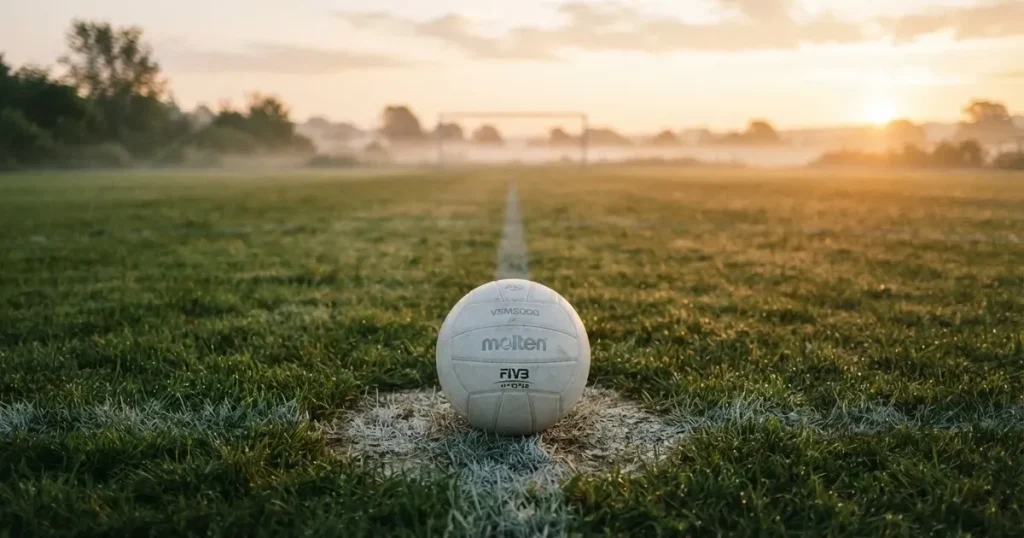 A ball on the centre spot of a grass pitch in morning light
